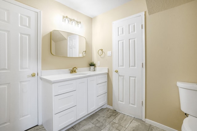 bathroom with toilet, baseboards, and vanity