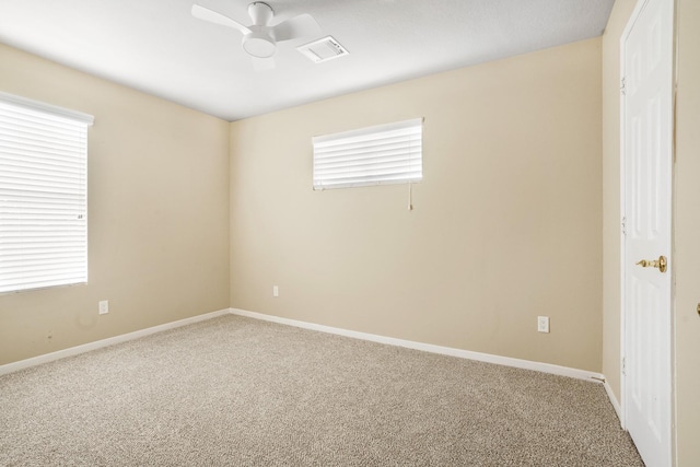 carpeted spare room featuring baseboards, ceiling fan, and visible vents