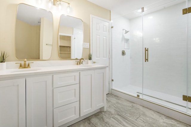 bathroom with double vanity, a sink, marble finish floor, and a shower stall