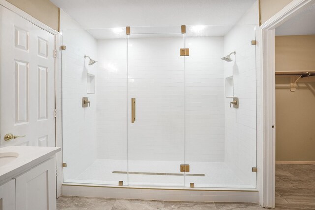 full bath featuring vanity, a walk in closet, and a shower stall