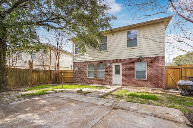 rear view of house featuring brick siding, a patio, a gate, and a fenced backyard