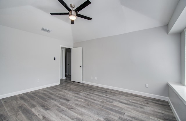 interior space featuring visible vents, wood finished floors, baseboards, ceiling fan, and vaulted ceiling