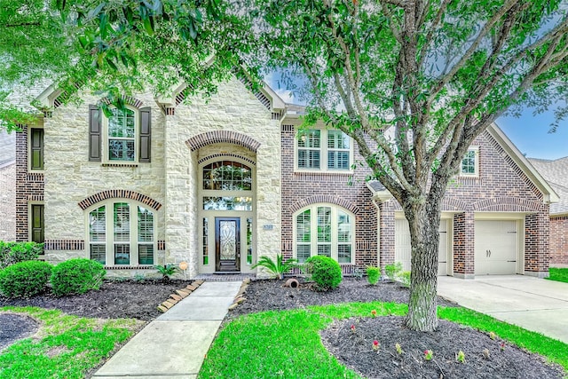 view of front facade featuring brick siding, a garage, driveway, and stone siding