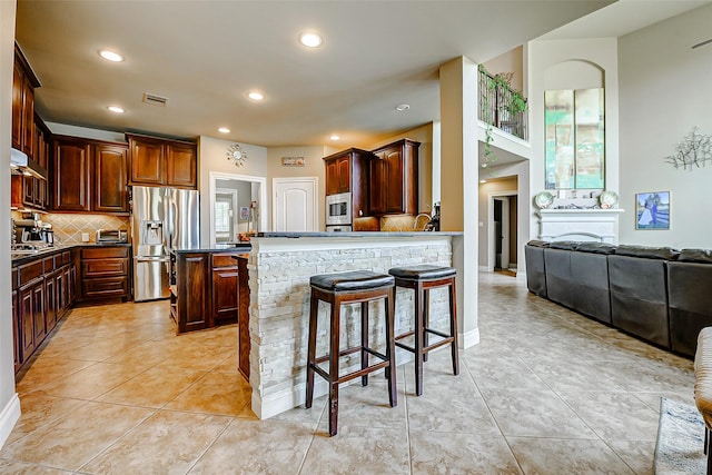 kitchen featuring a breakfast bar area, appliances with stainless steel finishes, tasteful backsplash, a peninsula, and recessed lighting