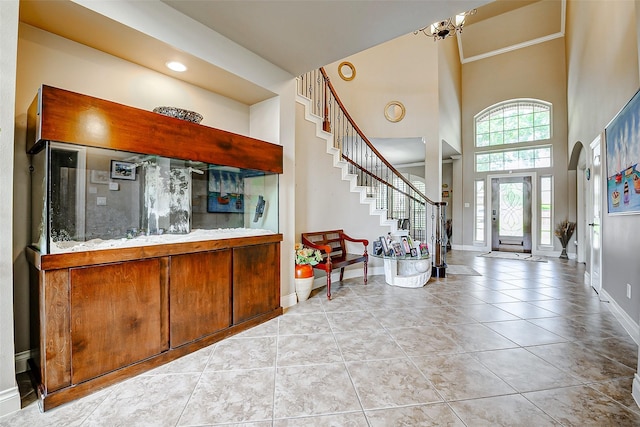 interior space with tile patterned flooring, stairs, a towering ceiling, baseboards, and a notable chandelier