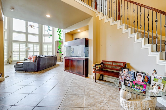 living room featuring stairs, ceiling fan, a high ceiling, recessed lighting, and tile patterned floors