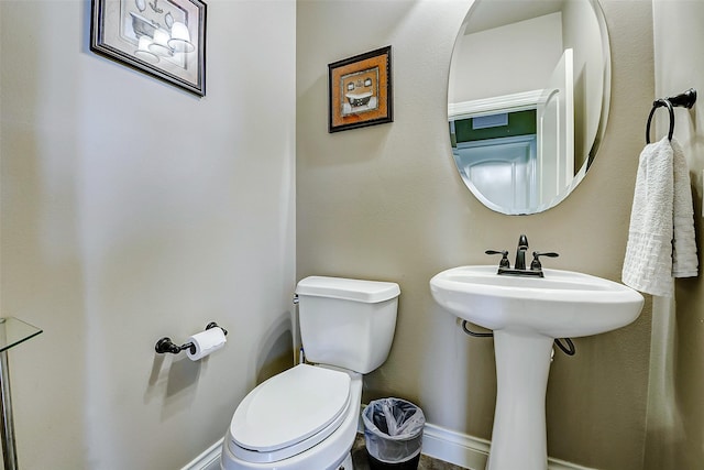 half bathroom with toilet and baseboards