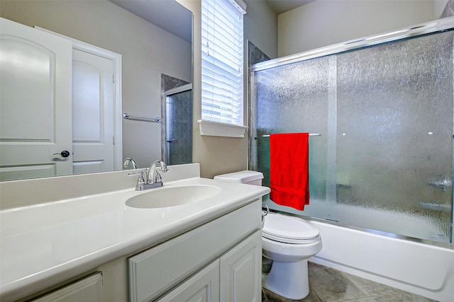 bathroom with vanity, bath / shower combo with glass door, tile patterned floors, and toilet