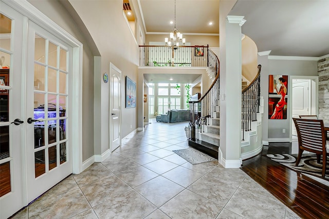 tiled foyer entrance with crown molding, baseboards, stairway, a chandelier, and french doors