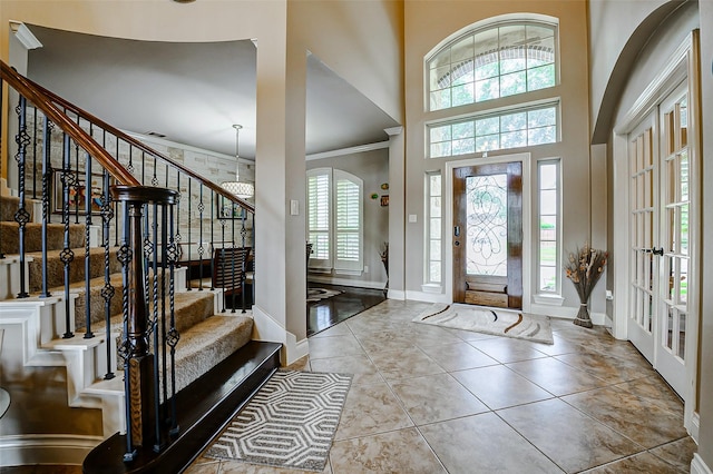 entrance foyer with baseboards, crown molding, a high ceiling, and stairway