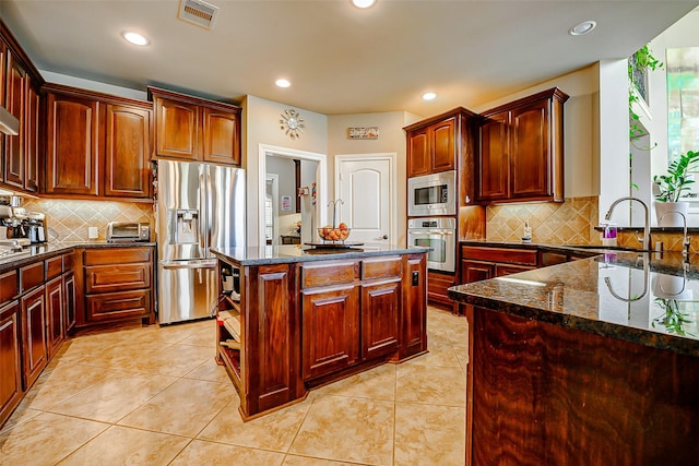 kitchen featuring visible vents, a sink, dark stone countertops, and appliances with stainless steel finishes