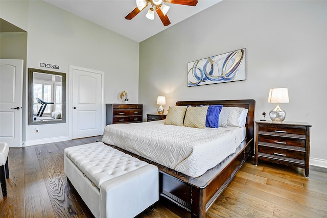 bedroom with baseboards, high vaulted ceiling, ceiling fan, and wood finished floors