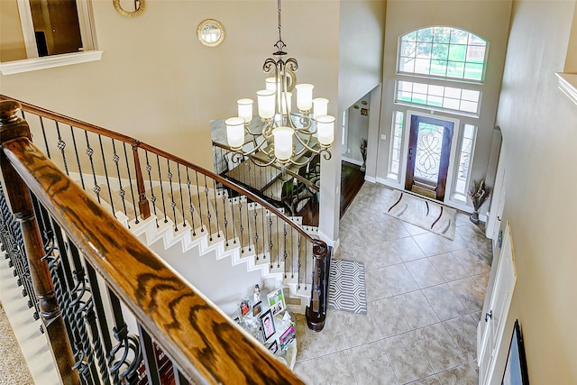 foyer featuring tile patterned flooring, baseboards, a notable chandelier, a high ceiling, and stairs
