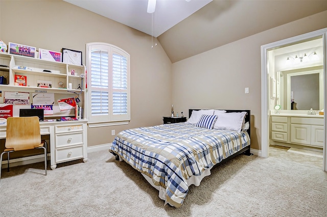 carpeted bedroom with ceiling fan, vaulted ceiling, built in desk, baseboards, and ensuite bathroom