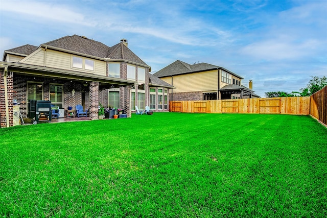 rear view of property featuring a patio, a fenced backyard, and a yard