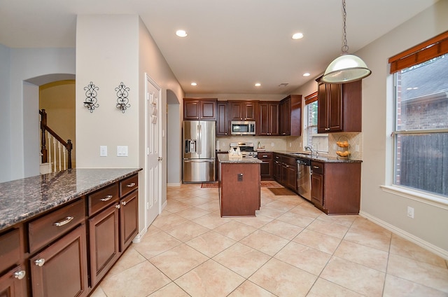 5018 Tramonte Trl, Katy, TX 77494 - kitchen featuring appliances with stainless steel finishes, arched walkways, dark stone countertops, recessed lighting, and a kitchen island
