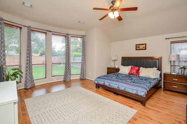 bedroom featuring multiple windows, vaulted ceiling, wood finished floors, and visible vents
