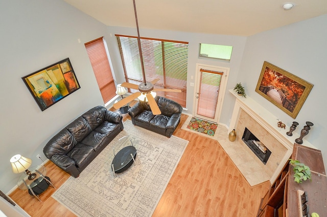 living room with baseboards, vaulted ceiling, wood finished floors, and a tile fireplace