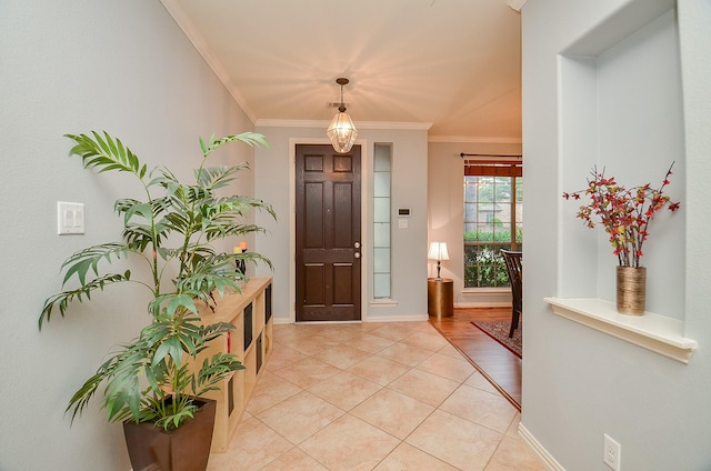 foyer featuring crown molding, light tile patterned flooring, and baseboards