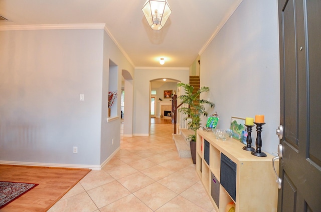 foyer with baseboards, arched walkways, light tile patterned flooring, and ornamental molding