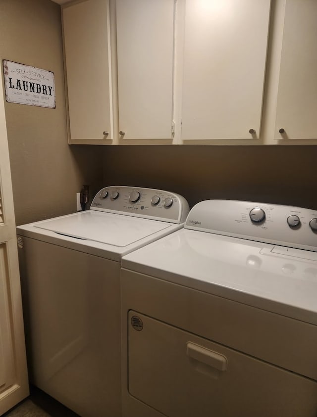 washroom featuring cabinet space and washer and clothes dryer