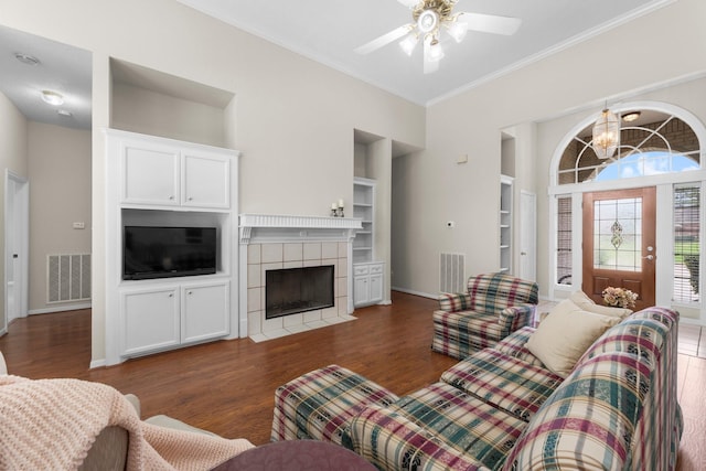 living room with built in features, ornamental molding, wood finished floors, and visible vents