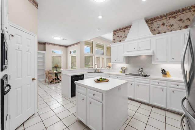 kitchen with a center island, a sink, light countertops, black appliances, and under cabinet range hood