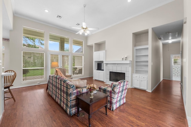living area with crown molding, ceiling fan, baseboards, and dark wood-type flooring