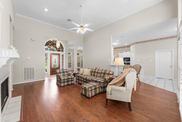 living room with visible vents, a fireplace with flush hearth, baseboards, and crown molding