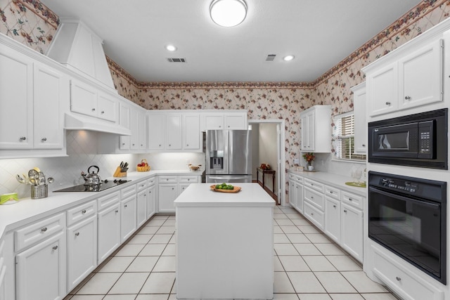 kitchen with a center island, white cabinets, black appliances, under cabinet range hood, and wallpapered walls