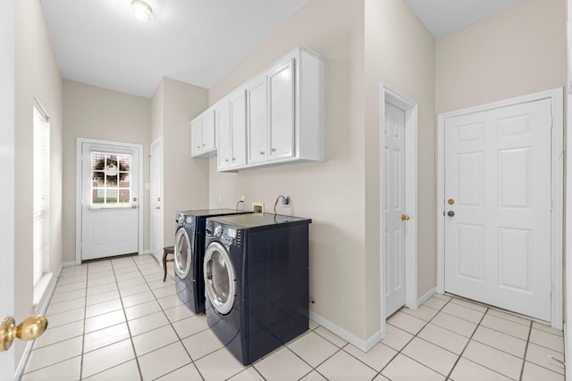 clothes washing area featuring separate washer and dryer, cabinet space, baseboards, and light tile patterned flooring