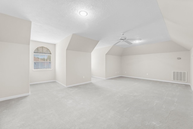 bonus room featuring ceiling fan, light carpet, baseboards, lofted ceiling, and visible vents