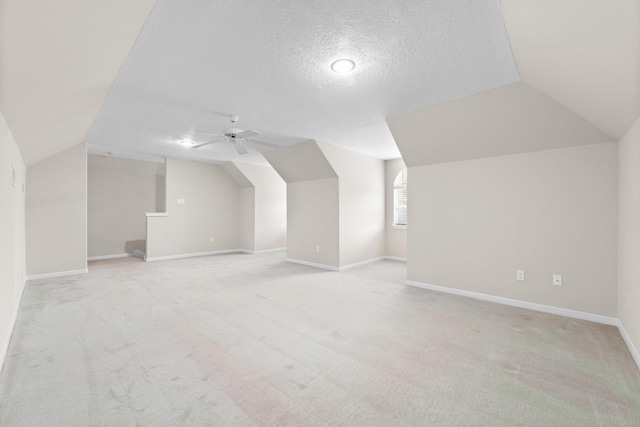 bonus room with a ceiling fan, a textured ceiling, baseboards, lofted ceiling, and light carpet