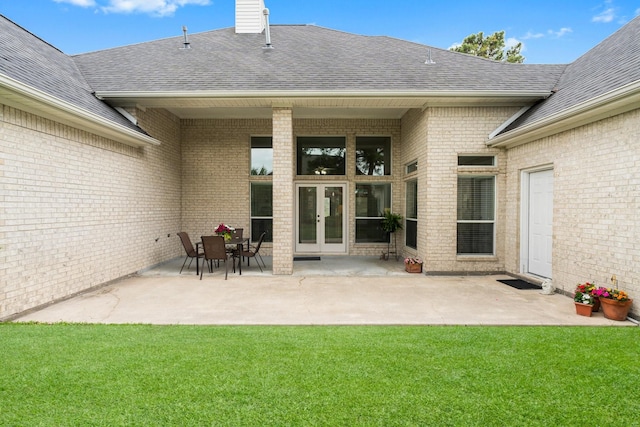 rear view of house featuring a shingled roof, a yard, and french doors