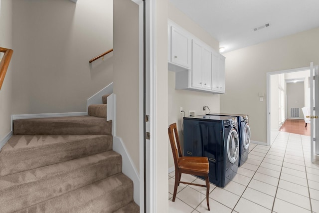 stairs featuring baseboards, visible vents, washing machine and dryer, and tile patterned flooring