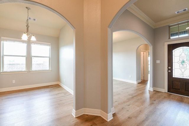 foyer entrance with arched walkways, ornamental molding, light wood finished floors, and visible vents