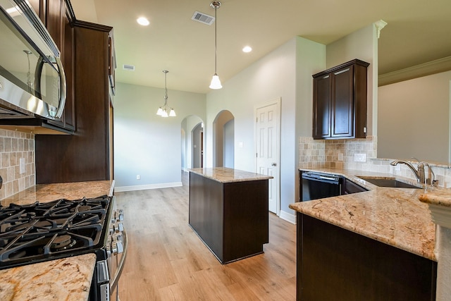 kitchen with dark brown cabinets, appliances with stainless steel finishes, a sink, arched walkways, and visible vents