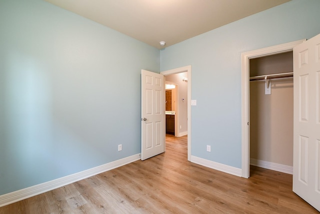 unfurnished bedroom featuring light wood-style floors, baseboards, and a closet