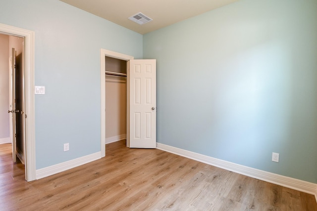 unfurnished bedroom featuring visible vents, light wood-style flooring, baseboards, and a closet