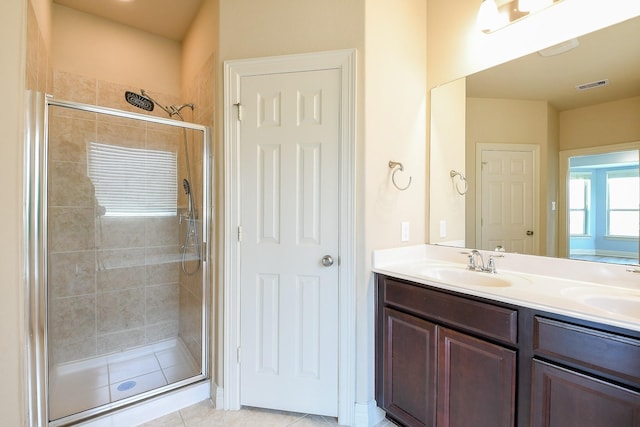 bathroom featuring double vanity, visible vents, tile patterned flooring, a shower stall, and a sink