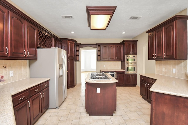 1321 E Archer Rd, Baytown, TX 77521 - kitchen featuring appliances with stainless steel finishes, visible vents, a center island, and reddish brown cabinets