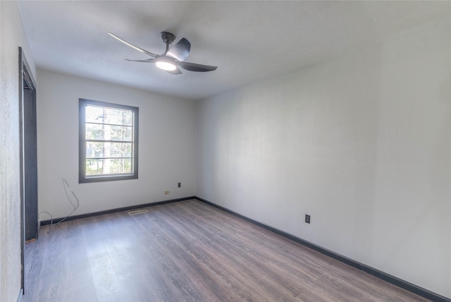 empty room with baseboards, ceiling fan, visible vents, and wood finished floors