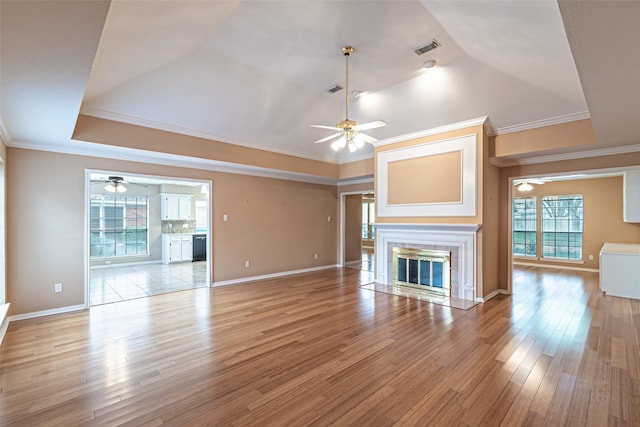 unfurnished living room with ceiling fan, ornamental molding, light wood-style flooring, and visible vents