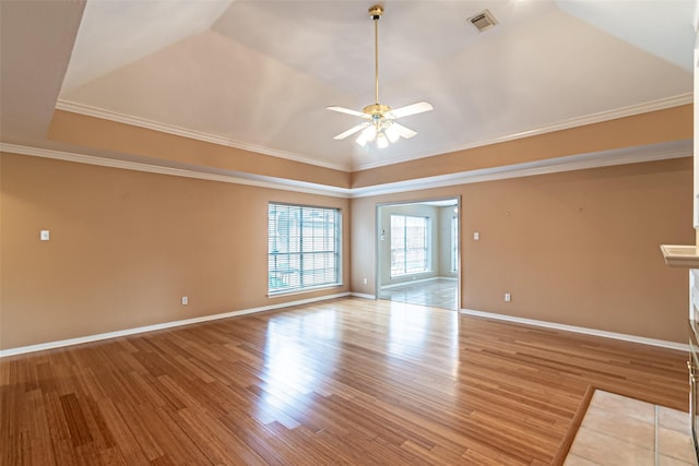 spare room with ceiling fan, visible vents, a raised ceiling, and light wood-type flooring