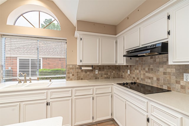 kitchen with black electric stovetop, a sink, decorative backsplash, lofted ceiling, and under cabinet range hood