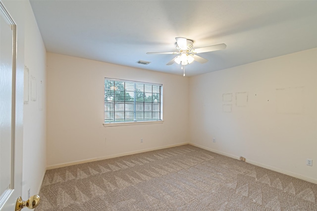 carpeted spare room with visible vents, baseboards, and ceiling fan