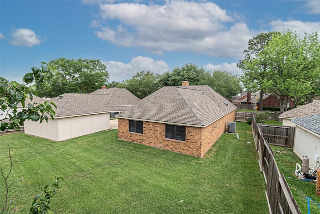 rear view of property featuring a yard, brick siding, central AC, and a shingled roof