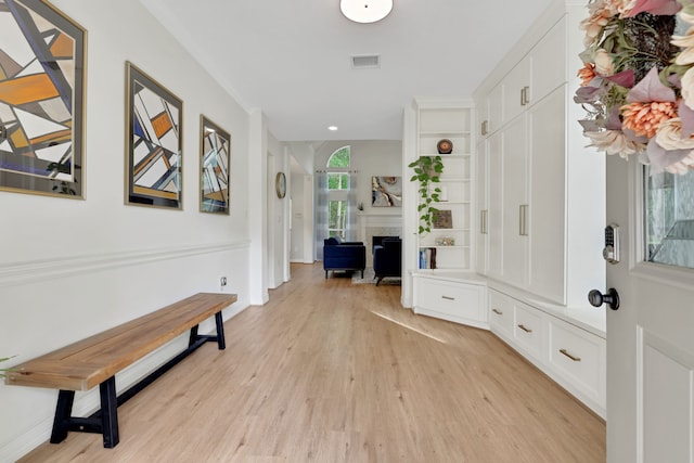 mudroom with a fireplace, baseboards, and light wood-style floors
