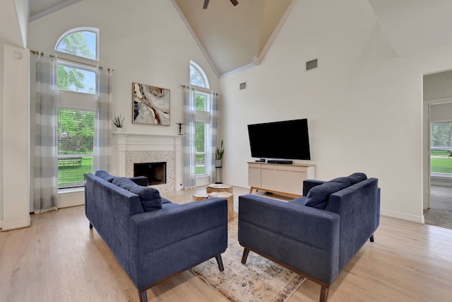 living area featuring high vaulted ceiling, baseboards, light wood-type flooring, and a tile fireplace