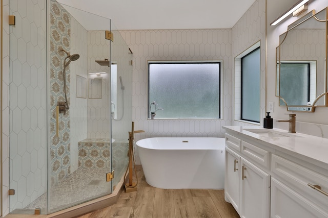 bathroom with vanity, a shower stall, wood finished floors, and a soaking tub